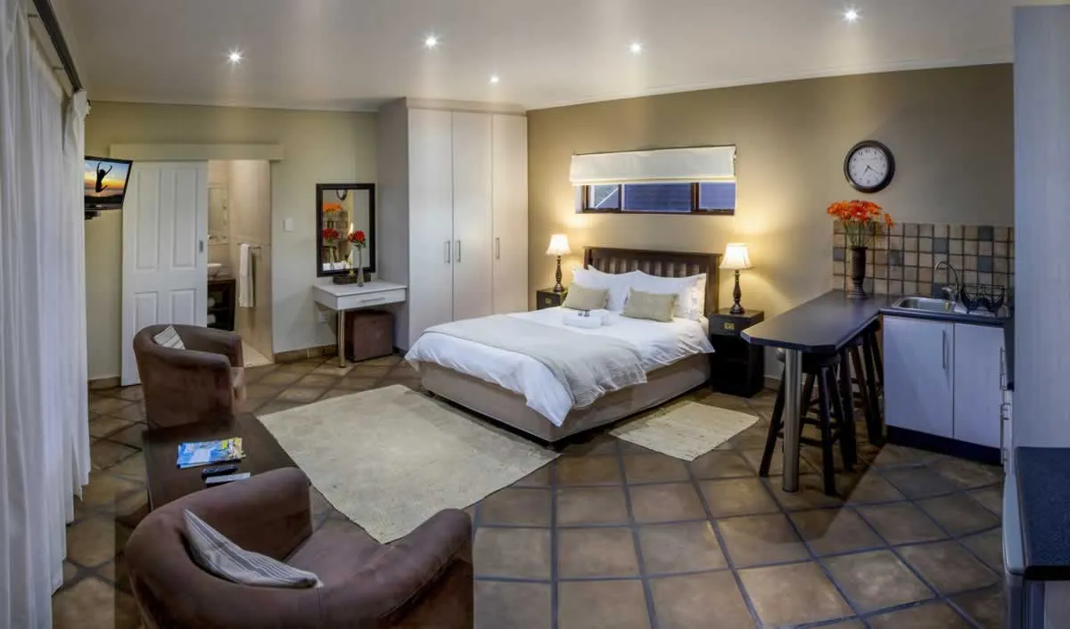 Cozy bedroom with bed seating area and small kitchenette