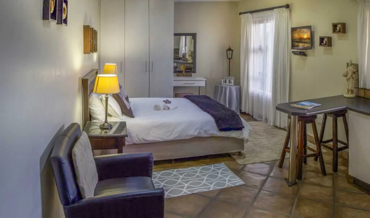 Cozy bedroom with bed armchair and small dining area with stools