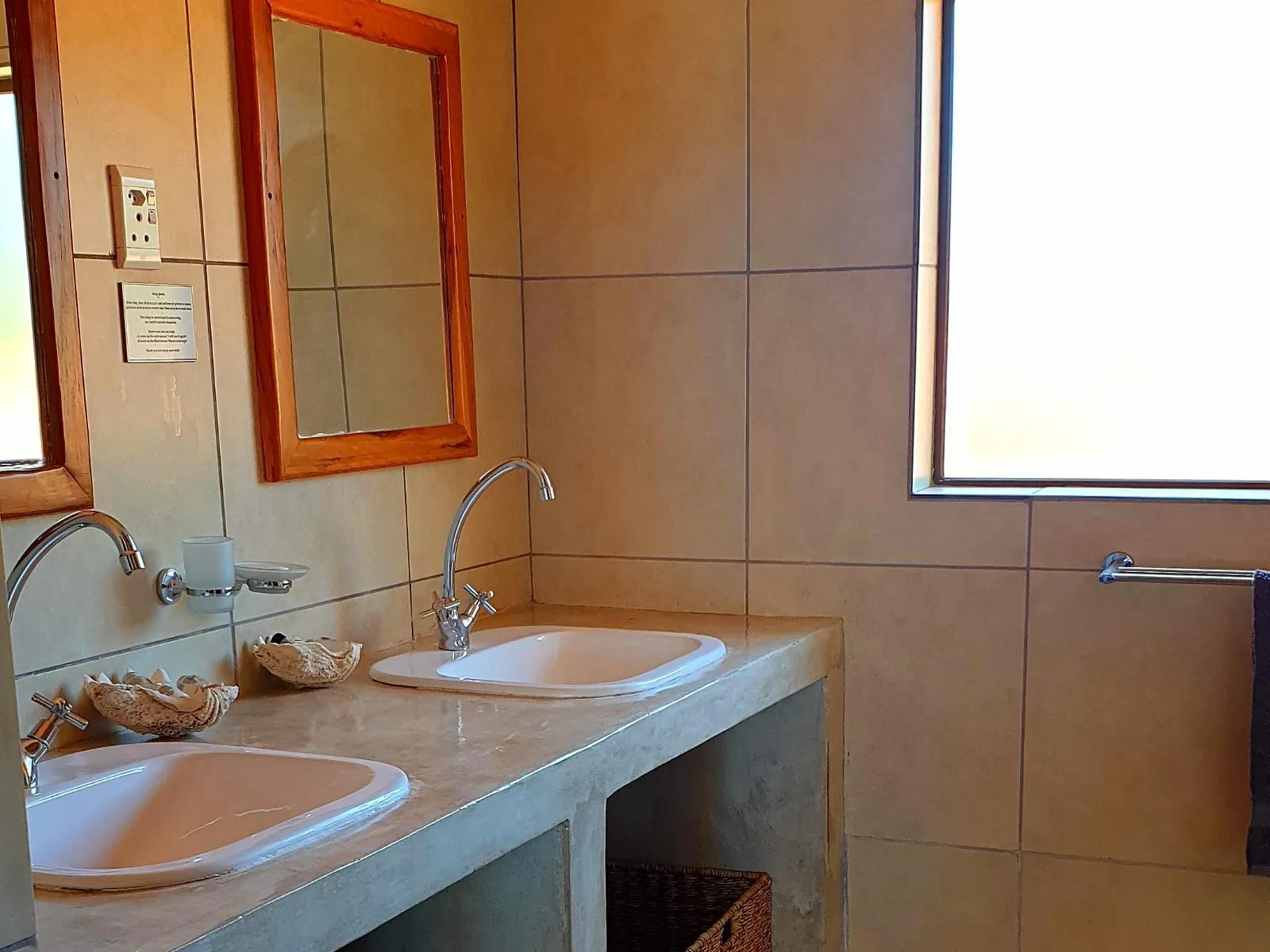 Double sink bathroom with mirror tiled walls and a window