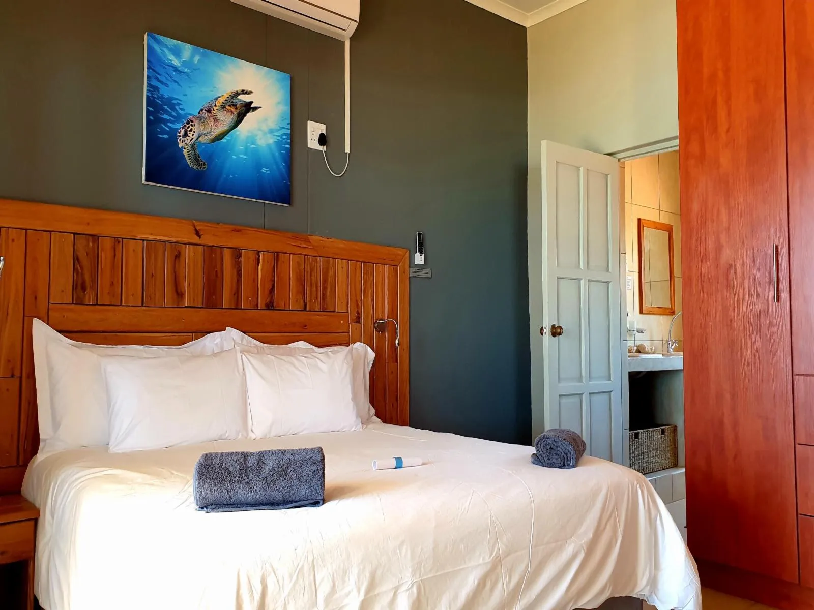 Bedroom with a wooden headboard neatly made bed and an oceanthemed picture