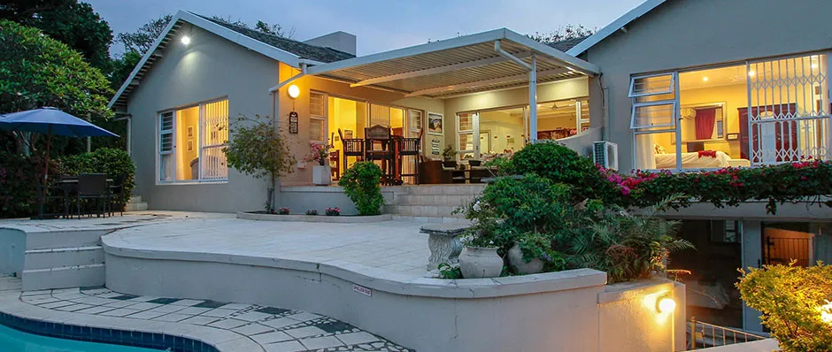 Modern house with pool at dusk lights on lush greenery