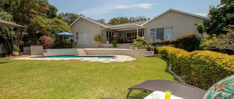 Backyard with pool lounge chairs and a house with a veranda
