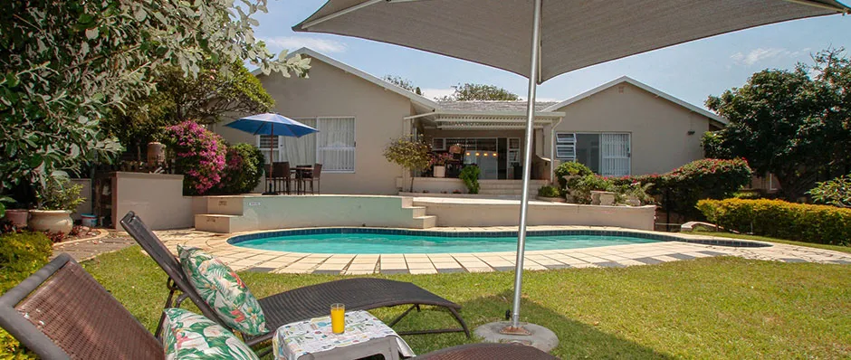 Backyard with pool lounge chairs and a house in the background