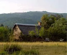 Stone cottage with a thatched roof in a rural hilly landscape