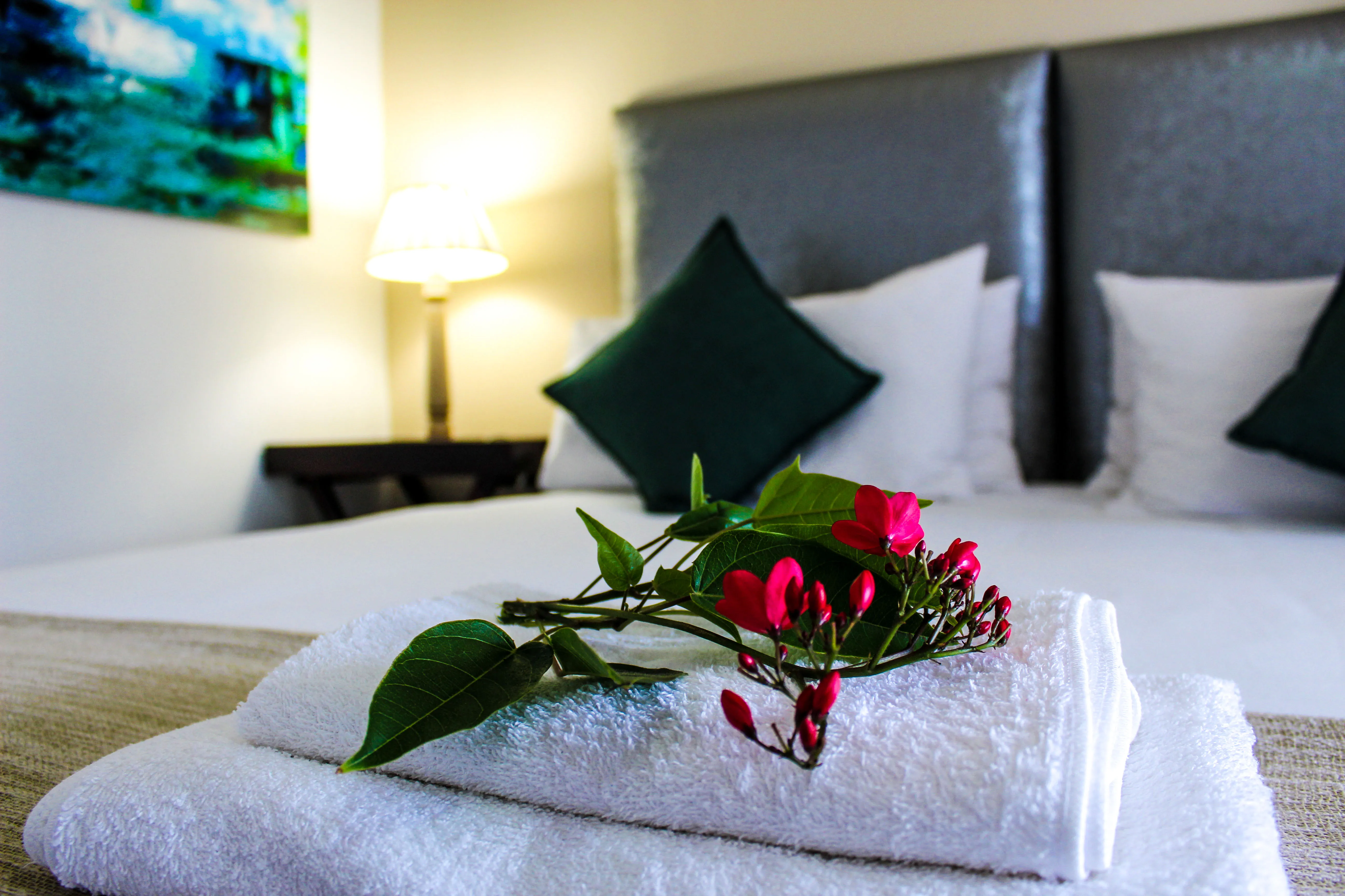 Fresh towels with red flowers on a bed in a cozy bedroom