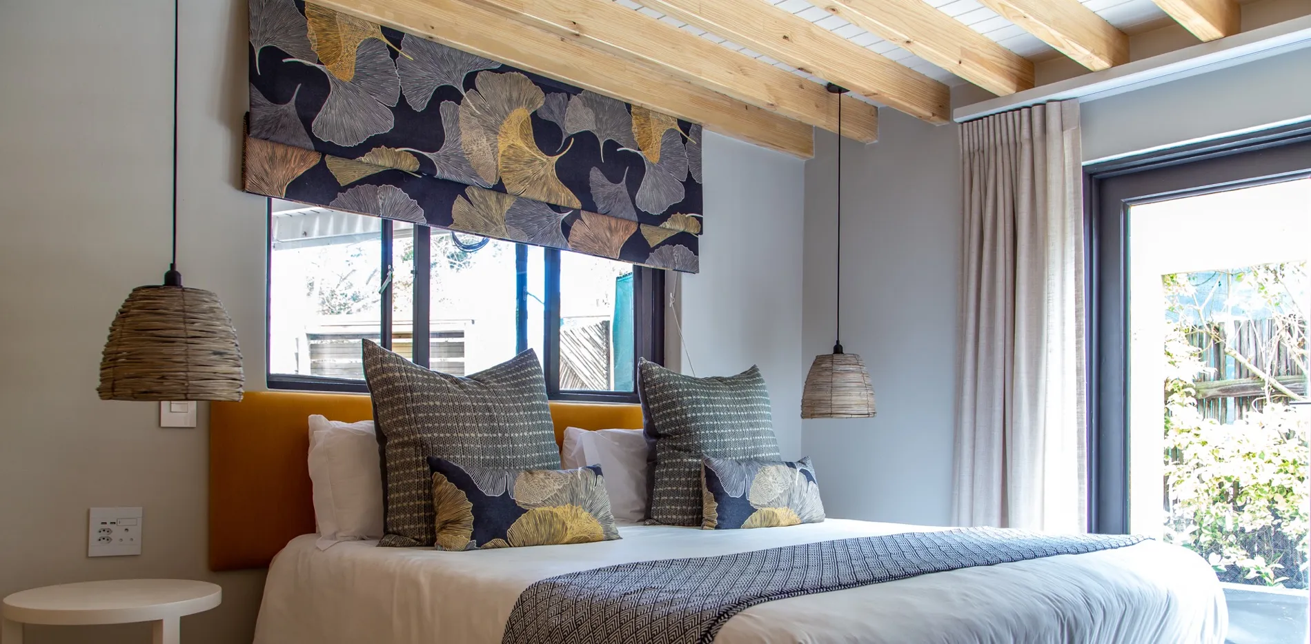 Cozy bedroom with large bed patterned pillows and exposed wooden ceiling beams