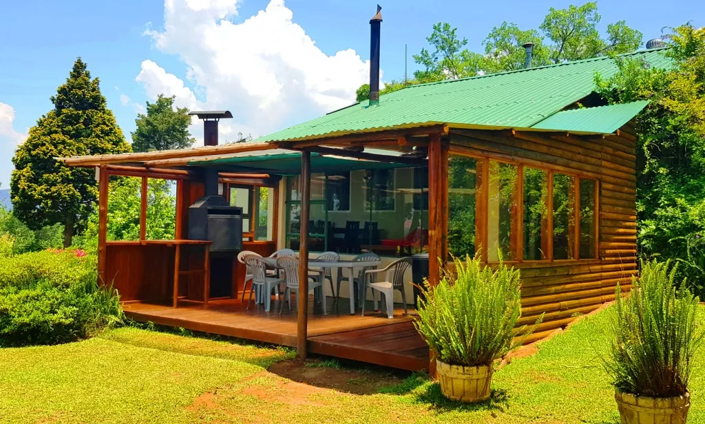 Wooden cabin with a green roof and outdoor seating area in a garden