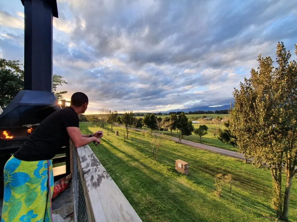 Person on a deck overlooking a scenic countryside at sunset
