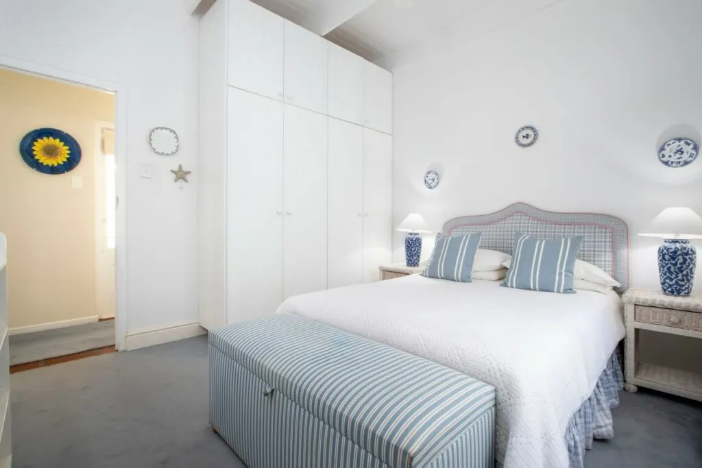 White bedroom with blue accents large bed and builtin wardrobes
