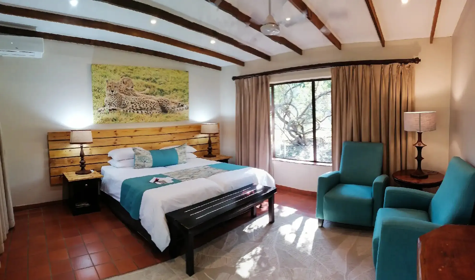 Bedroom with large bed wooden headboard and two armchairs near a window