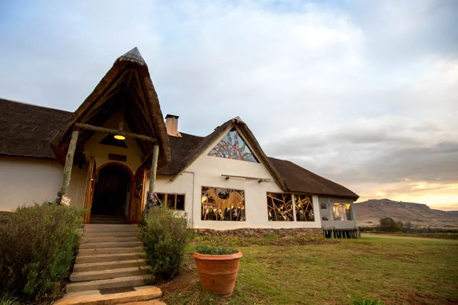 Thatchedroof building with steps leading to entrance surrounded by greenery and mountains
