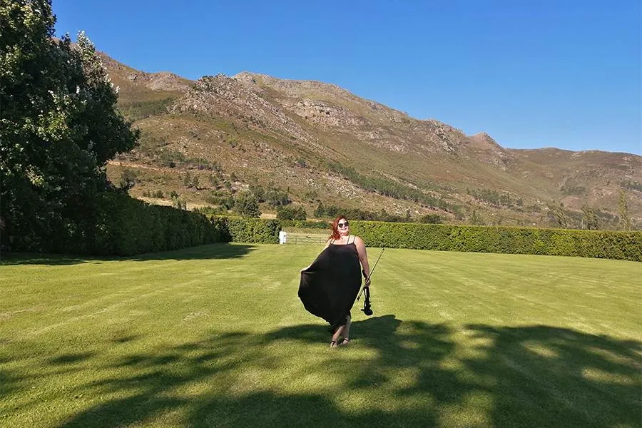 Woman in black dress walking on grass with mountains in the background