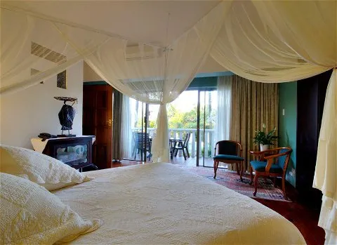 Bedroom with canopy bed open doors to balcony and seating area