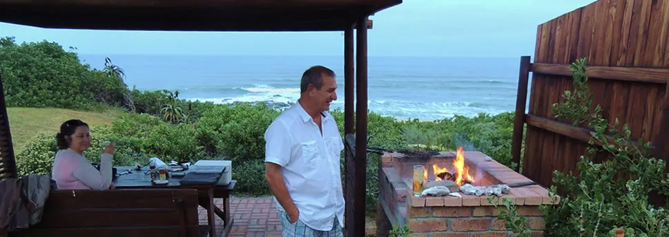 Man and woman on a patio with ocean view and a fire pit