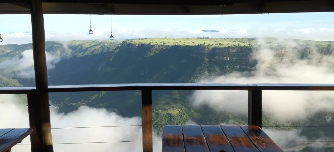 Wooden tables on a balcony overlooking a misty valley and distant hills