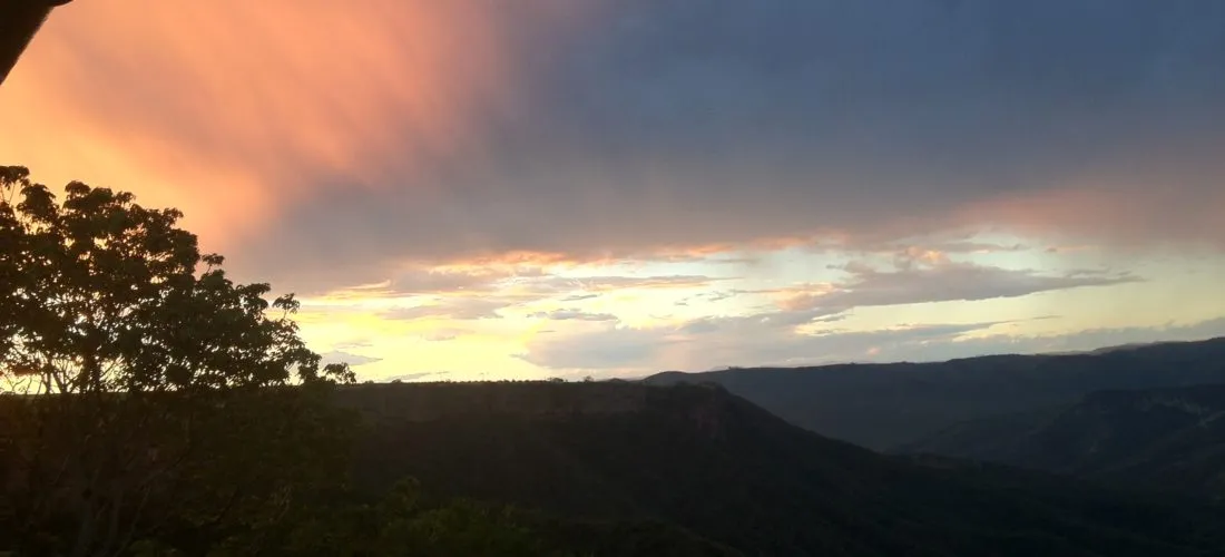 Sunset over a valley with colorful sky and silhouetted trees