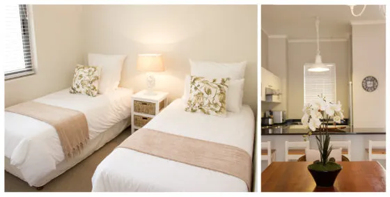 Two neatly made beds in a bedroom and a dining area with a plant