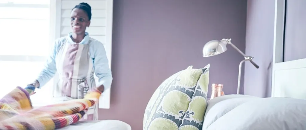 Woman arranging colorful blanket in a bedroom with modern decor