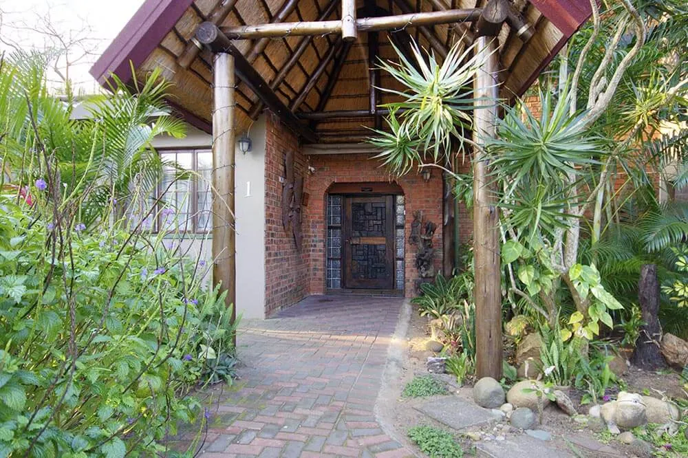 Entrance to a house with a brick pathway and lush greenery
