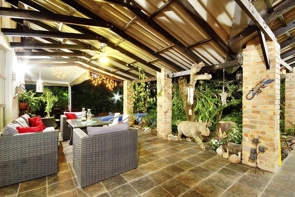 Outdoor patio with wicker furniture plants and decorative elements under a covered roof