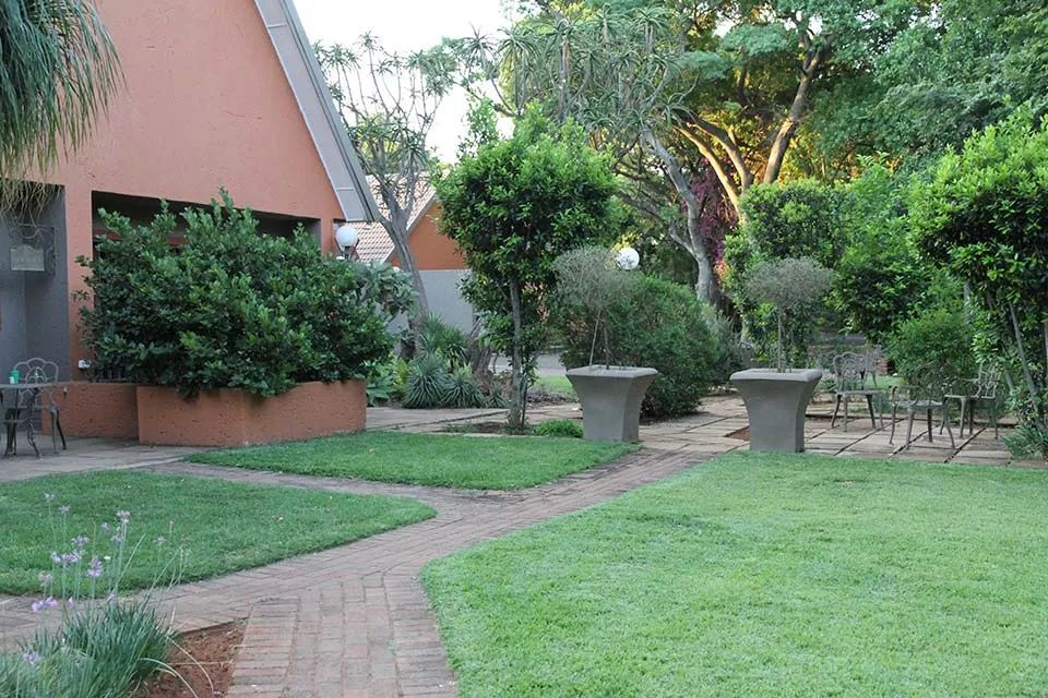 Garden with brick path green lawn and modern outdoor furniture near a building