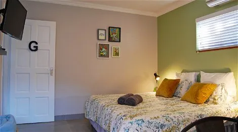 Cozy bedroom with a floral bedspread wall art and a TV on the door