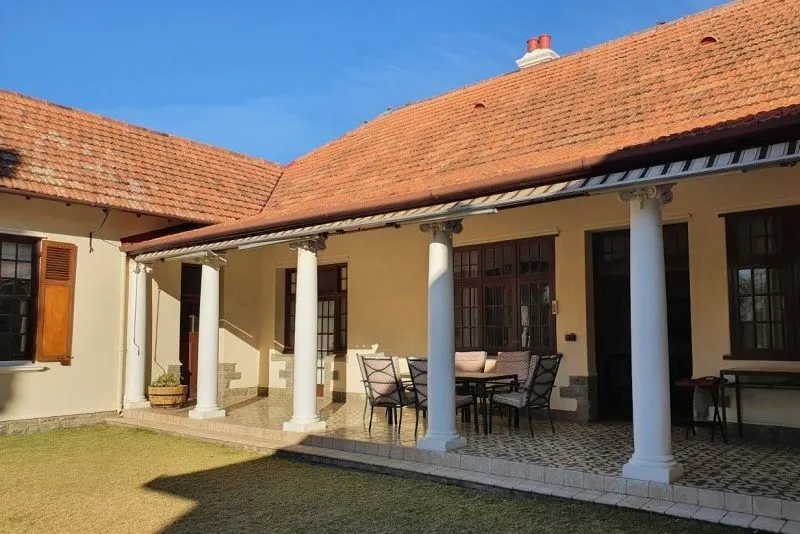 House with tiled roof veranda columns and outdoor seating area in sunlight