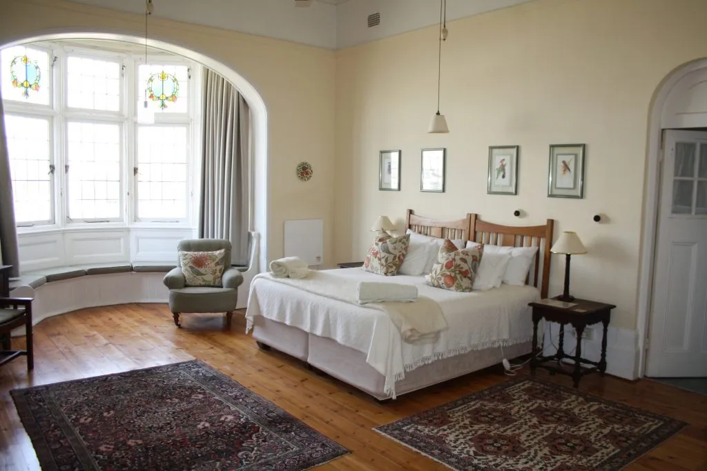 Bedroom with large bed armchair and stained glass windows in a cozy setting