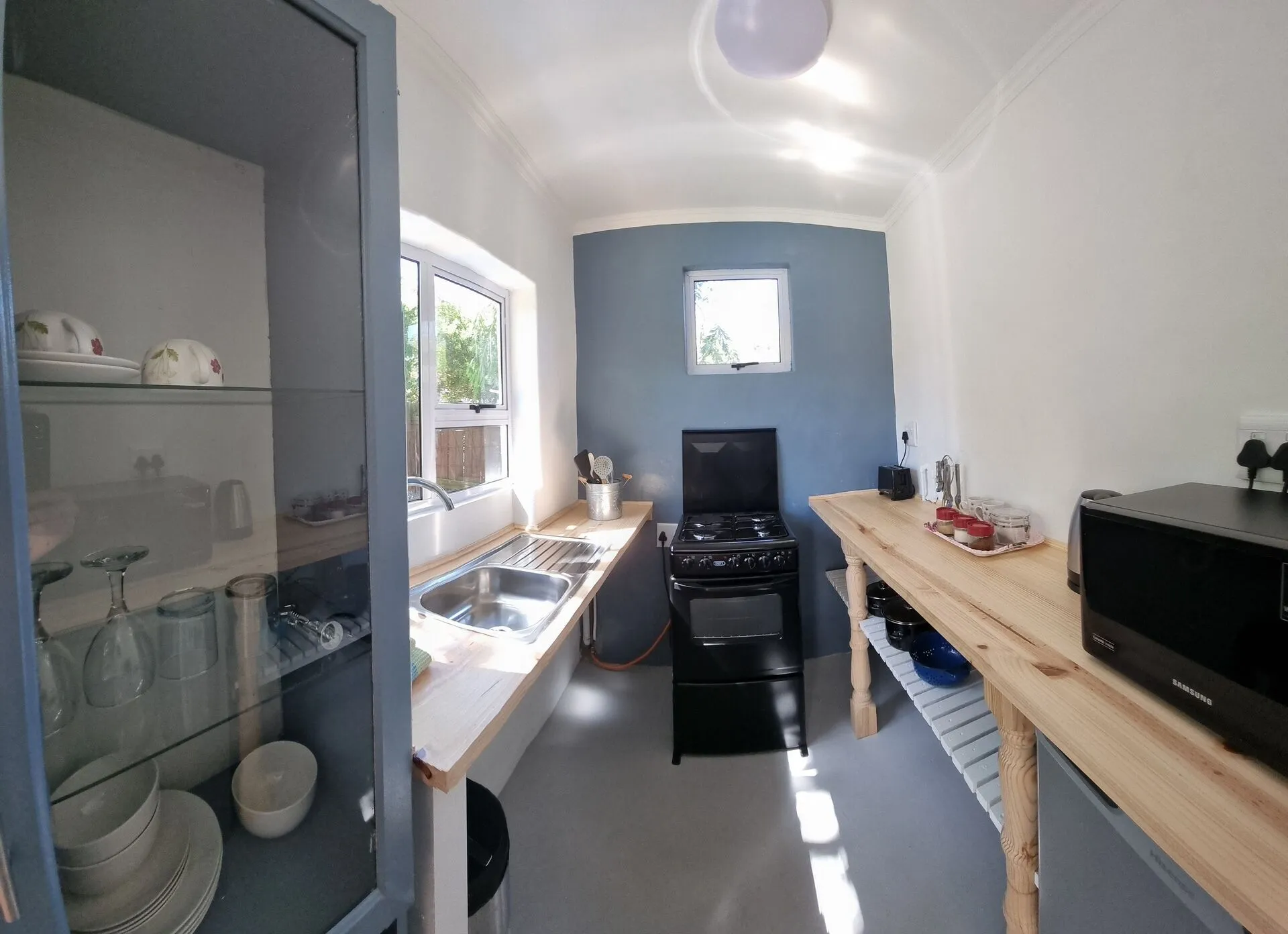 Small kitchen with sink stove wooden counter and glass cabinet