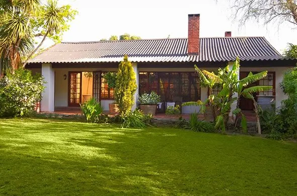 Singlestory house with large windows surrounded by greenery and a wellkept lawn