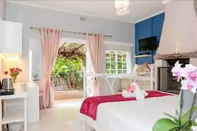 Cozy bedroom with a fireplace TV and view of a garden through French doors