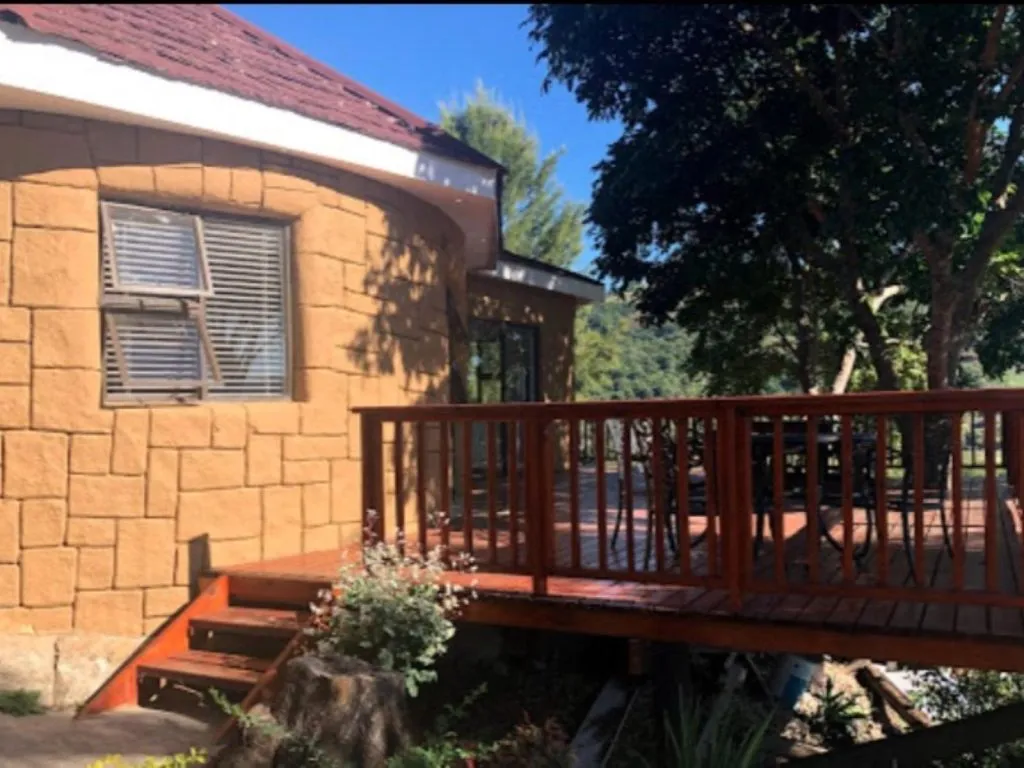 House with wooden deck plants and trees in a sunny outdoor setting