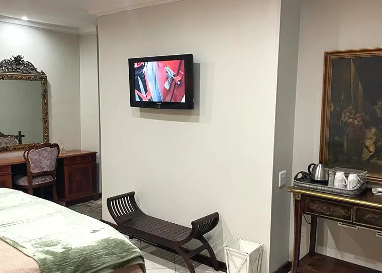 Bedroom with wallmounted TV wooden bench desk mirror and painting