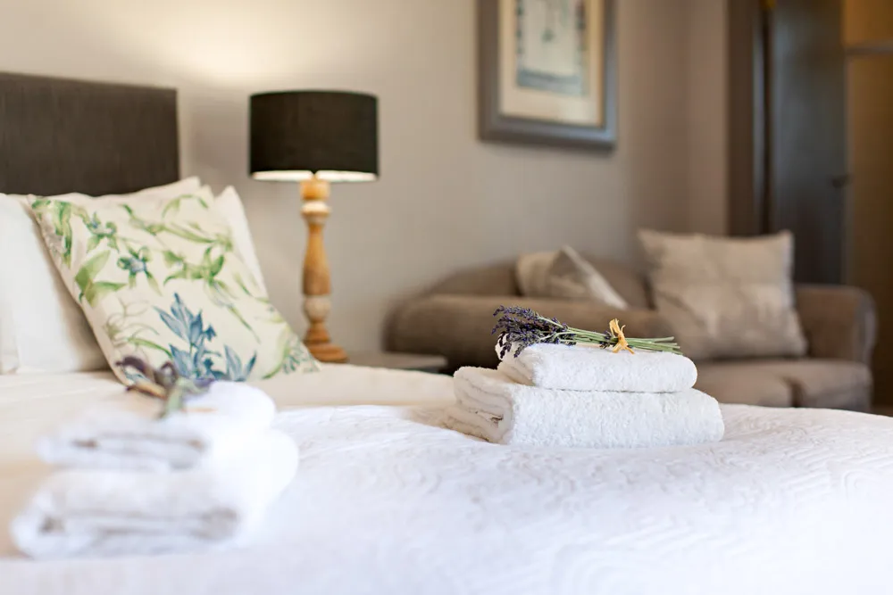 Bed with folded towels floral pillow and lamp in a cozy bedroom