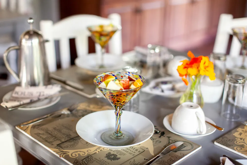 Colorful fruit cocktail in a glass on a set dining table with flowers