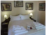 Neatly made bed with white linens and towels in a decorated bedroom