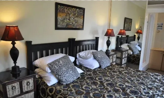 Bedroom with two beds black headboards patterned bedding and bedside lamps