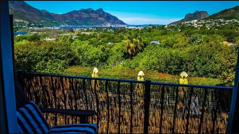 View of mountains and greenery from a balcony with striped chair