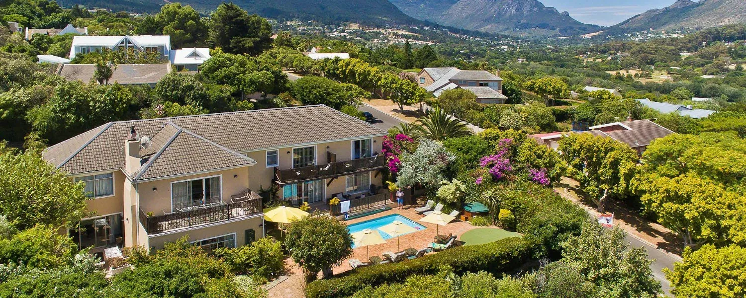 Large house with pool surrounded by lush greenery and distant mountains