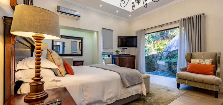 Cozy bedroom with large bed lamp armchair and open view to garden