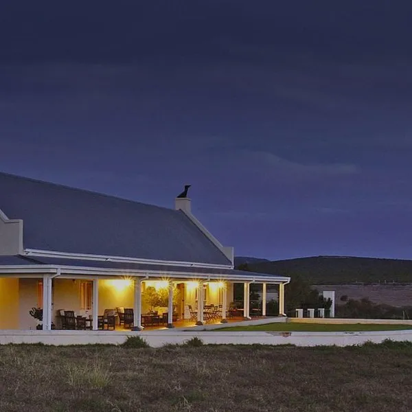 Country house at dusk with a veranda and outdoor seating