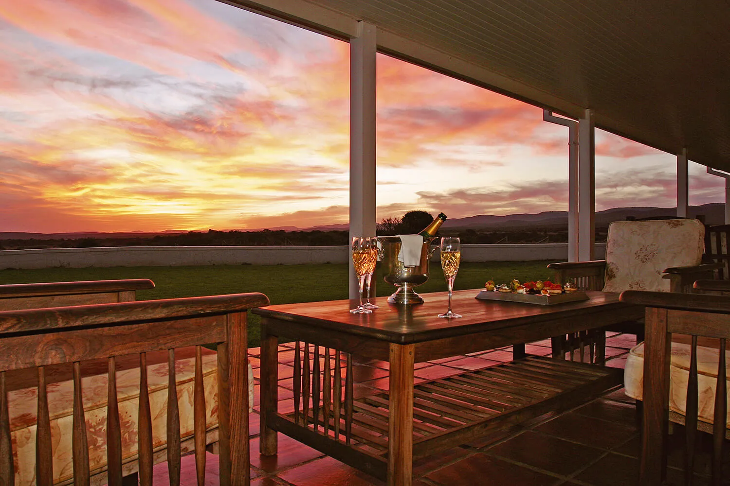 Wooden patio furniture with champagne glasses and sunset view
