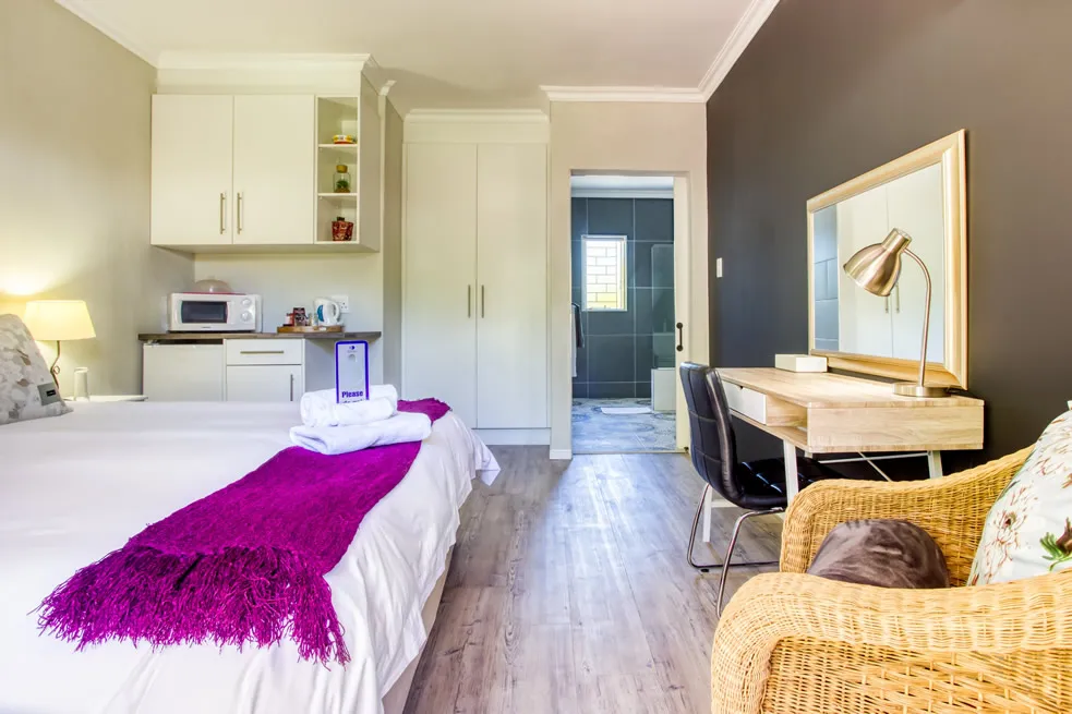 Modern bedroom with bed desk and kitchenette in a small apartment