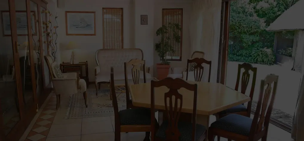 Dining area with wooden table and chairs adjacent to a living room with sofas