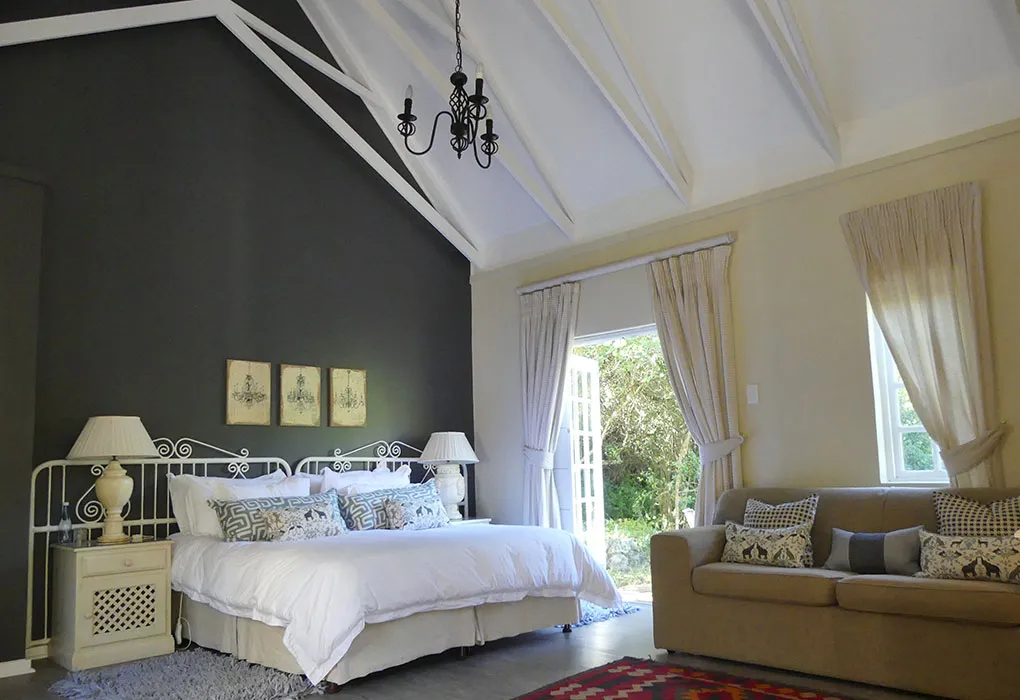 Bedroom with a large bed sofa and open French doors to a garden