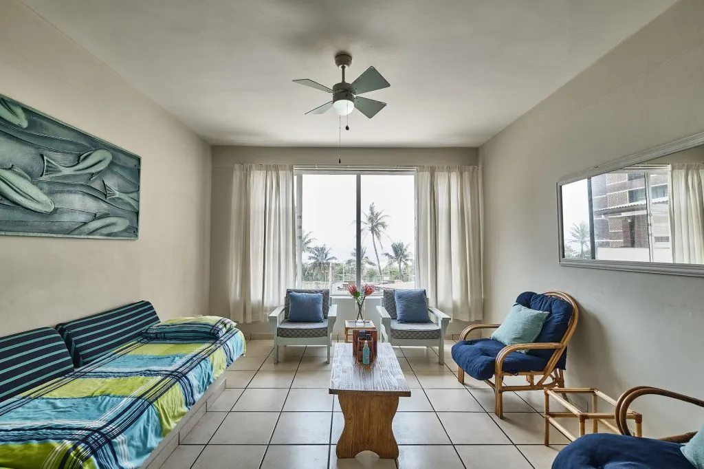 Bright living room with colorful sofa chairs and large window with ocean view