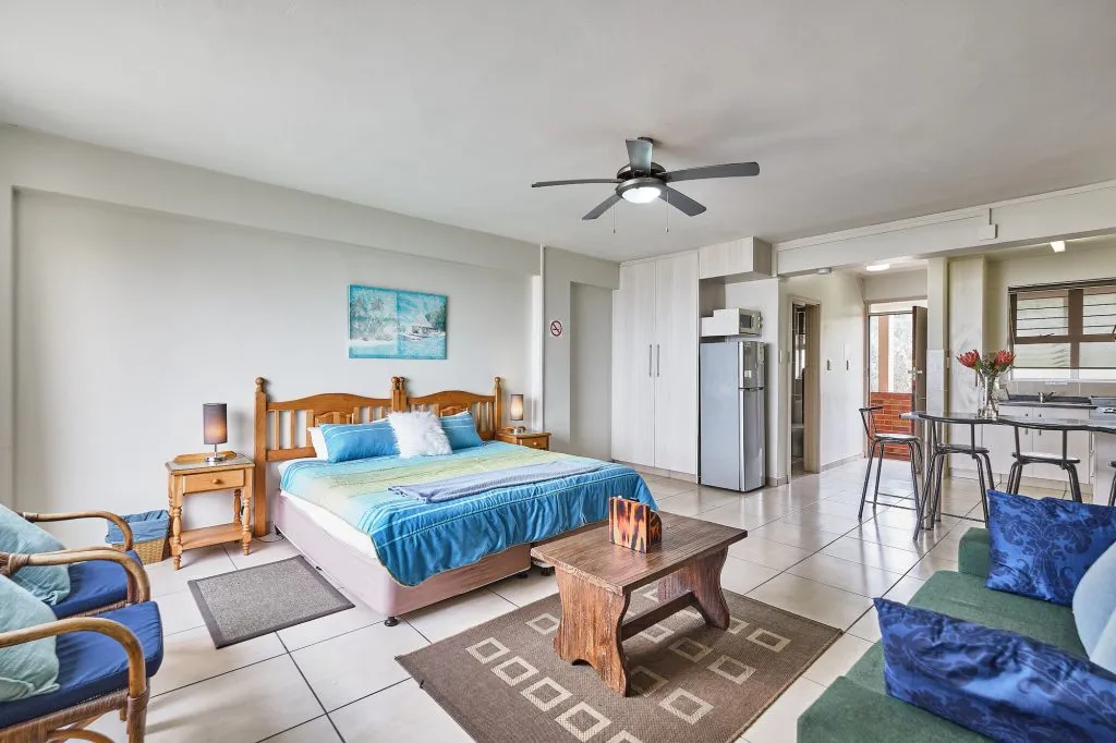 Cozy bedroom with a bed sofa and kitchenette in the background