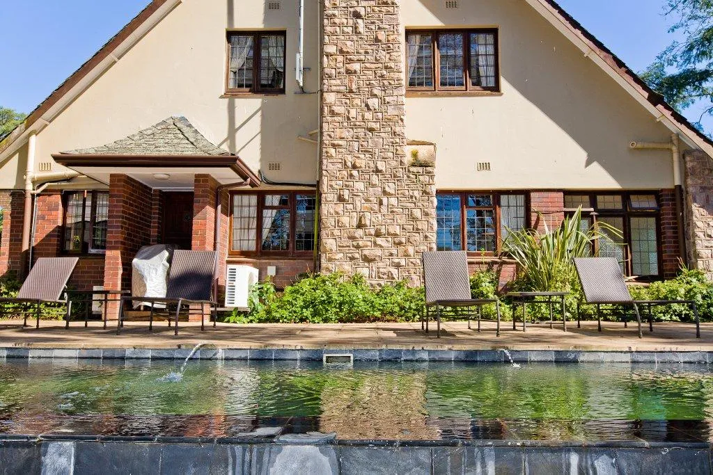 Stone and stucco house with pool lounge chairs and windows in sunny setting