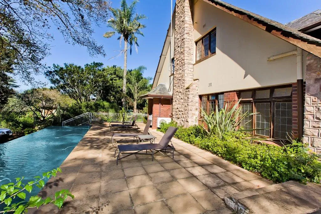 Swimming pool with lounge chairs on a patio next to a house
