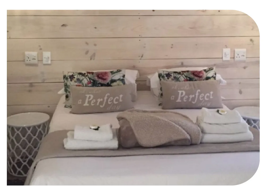 Cozy bed with pillows towels and a blanket in a wooden room